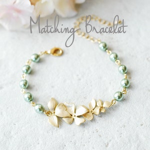May include: Gold-coloured bracelet with a floral design and green pearl beads. The bracelet has a delicate chain and a clasp closure. The text "Matching Bracelet" is written in cursive.