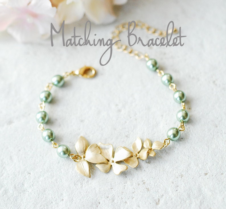 May include: Gold-coloured bracelet with a floral design and green pearl beads. The bracelet has a delicate chain and a clasp closure. The text "Matching Bracelet" is written in cursive.