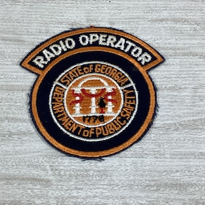 May include: A blue and orange embroidered patch with the text "Radio Operator" and the seal of the "State of Georgia Department of Public Safety".