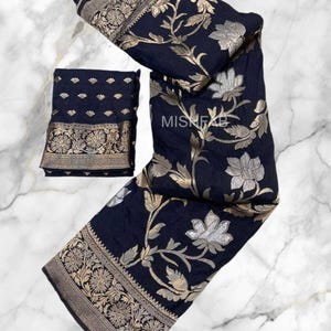 May include: Dark navy blue textile with silver and gold floral patterns. The fabric has a detailed border with floral and geometric designs. The set includes a folded piece and a larger, draped section, showcasing the textile's design.