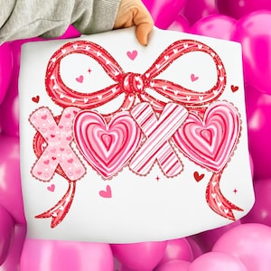 May include: A white sheet featuring a red bow and the letters "XOX" in a Valentine's Day design. The letters are decorated with hearts and stripes in shades of pink and red. Small hearts and stars are scattered around the design.