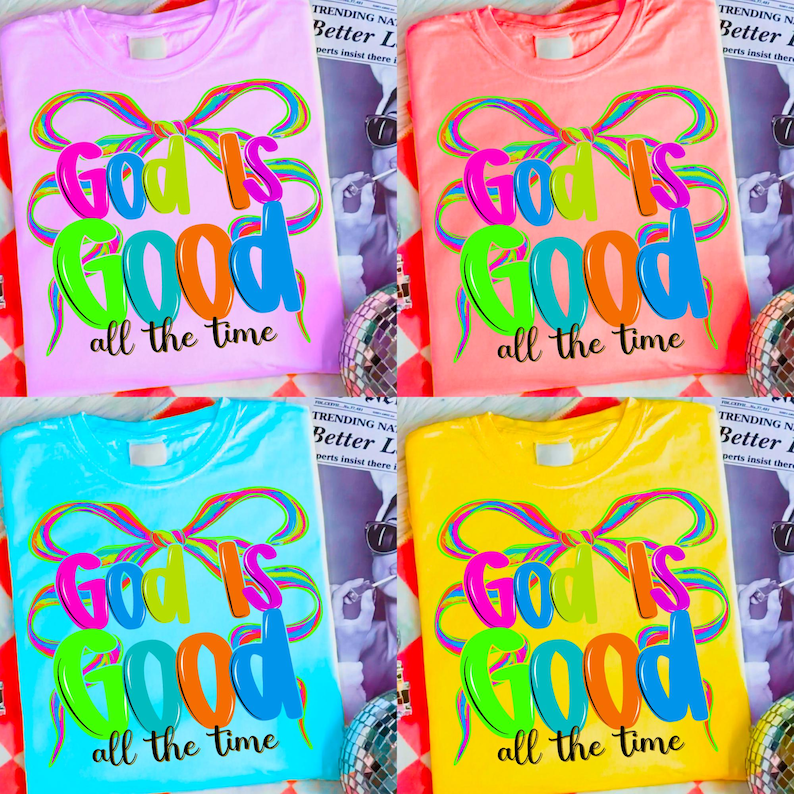 May include: Four colorful t-shirts: pink, coral, blue, and yellow. Each shirt features the text "God is Good all the time" in vibrant, multi-colored letters and a decorative bow design. The shirts are displayed on a patterned surface.