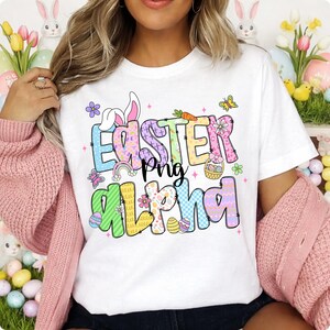 Op de afbeelding: Wit T-shirt met de tekst "Easter Png Alpha" in kleurrijke, patroonletters. Het ontwerp bevat paaseieren, vlinders, bloemen en een regenboog. Een feestelijk ontwerp met een lentethema.