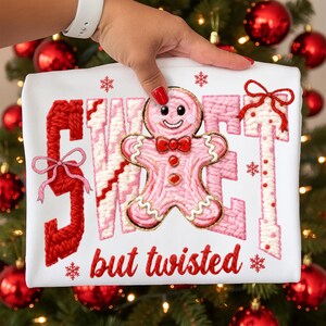 May include: White t-shirt with a pink gingerbread man and the words "SWEET but twisted" in red. The design includes red bows and snowflakes, perfect for the holiday season.