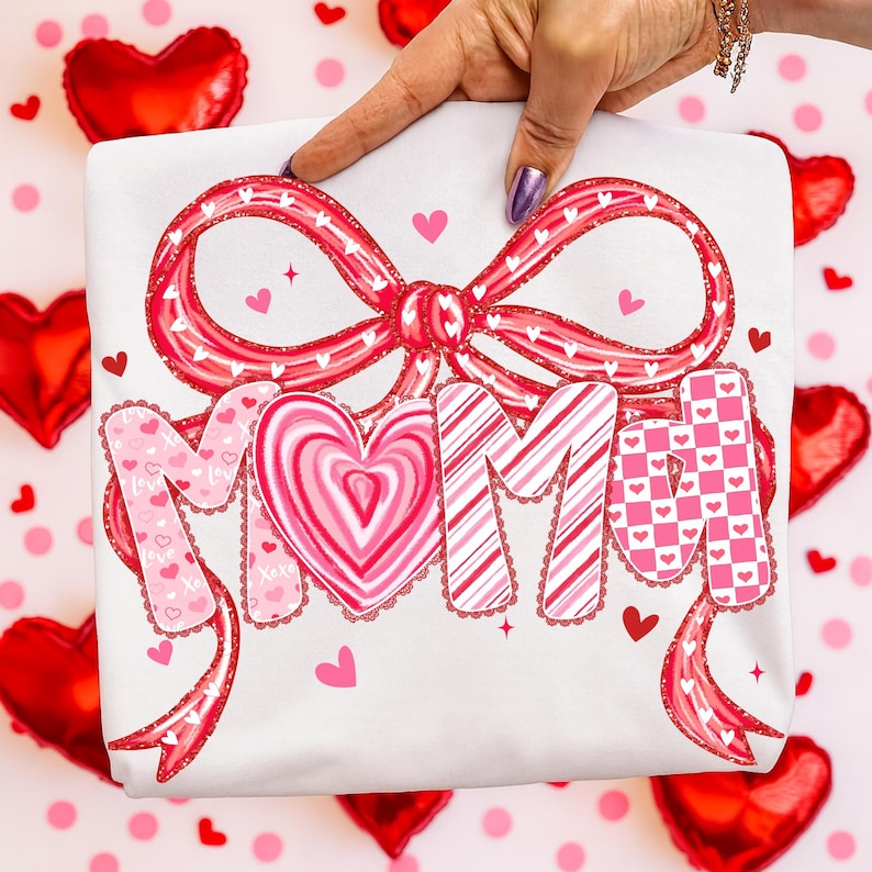 May include: White t-shirt with a large red bow and the word "MIMI" in pink and red lettering. The "O" in MIMI is a heart shape. Small hearts and decorative ribbons are also featured.