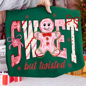 May include: A green Christmas graphic featuring the words "SWEET" and "but twisted" in red and white. A pink gingerbread man with a red bow tie is in the center. Pink bows and snowflakes are also featured in the design.