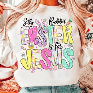 May include: White sweatshirt with a colorful Easter graphic. The design features the text "Silly Rabbit Easter is for Jesus" in a playful font, along with Easter eggs, a bunny, and a rainbow.