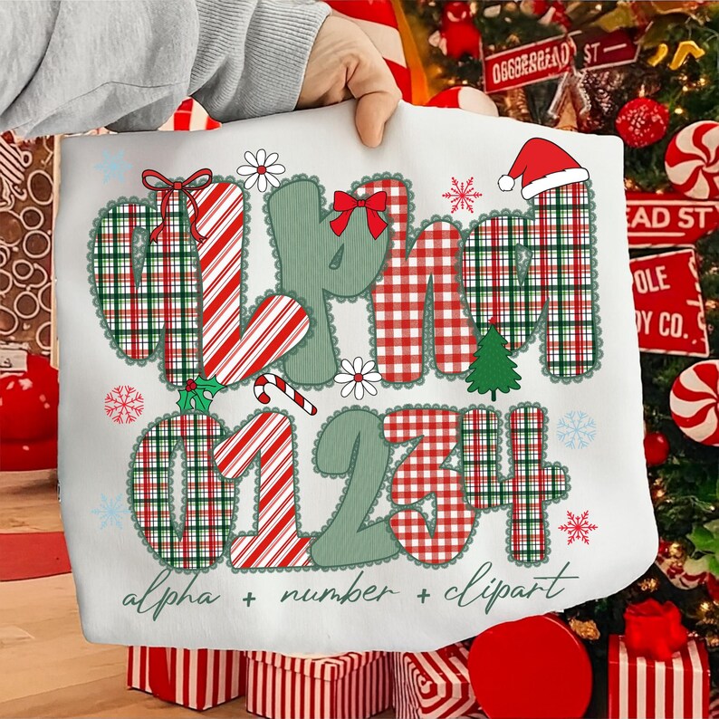 May include: White Christmas-themed graphic with the words "MERRY" and numbers "01234" in a plaid pattern. The design includes a Santa hat, snowflakes, and the text "alpha + number + clipart".