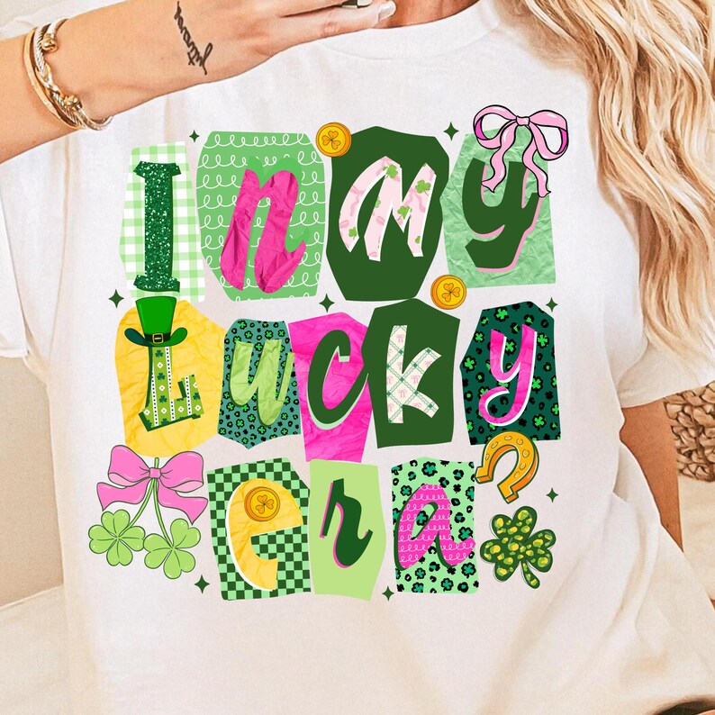 May include: White t-shirt with a colorful graphic design that says "I'm my lucky era." The design includes green, pink, and yellow elements, such as shamrocks, bows, and a horseshoe. The shirt is perfect for St. Patrick's Day.