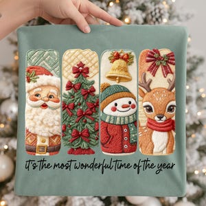 May include: A sage green Christmas pillow featuring embroidered holiday designs. The designs include Santa Claus, a Christmas tree, a snowman, and a reindeer. The text "It's the most wonderful time of the year" is written at the bottom.