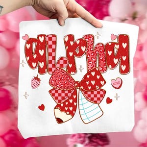 May include: White tote bag with the word "Alpha" in red, heart-filled letters. A large red bow with a pencil and notebook design is below the text. Additional elements include hearts, a strawberry, and the text "XOXO".