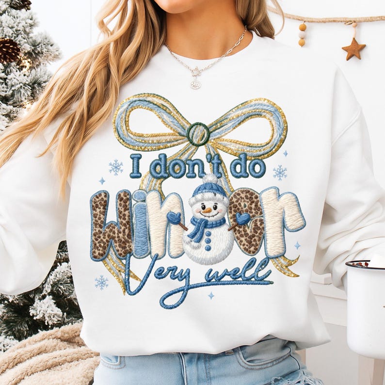 May include: White sweatshirt with a large embroidered design. The design features a bow, snowflakes, and a snowman with the text "I don't do winter very well". The word "winter" has a leopard print pattern.