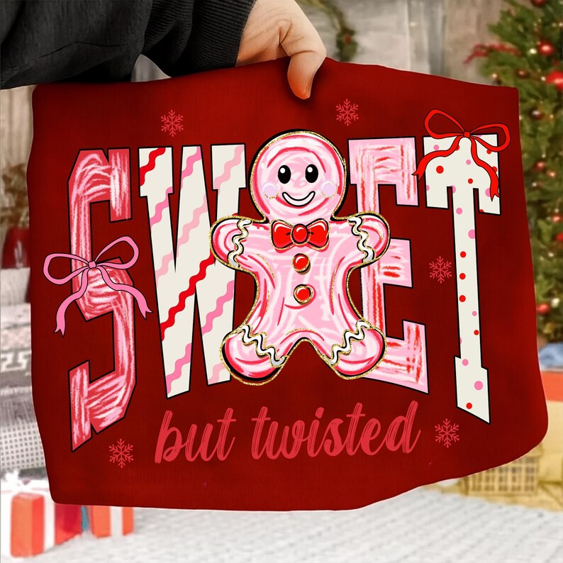 May include: A festive red cushion featuring the words "SWEET but twisted" in white and pink. A gingerbread man with a red bow tie is in the center. Pink bows and snowflakes decorate the cushion.