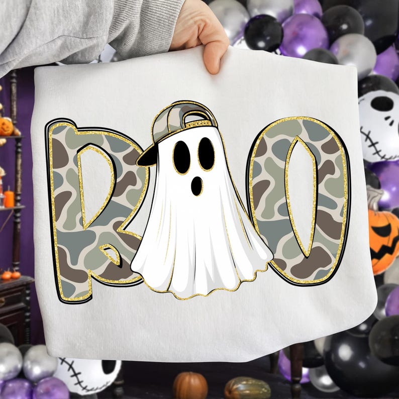 May include: White Halloween-themed sweatshirt with the word "BOO" in a camouflage pattern with gold trim. The "O" features a ghost wearing a camouflage baseball cap. The design is perfect for Halloween.