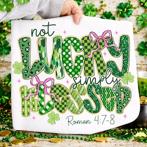 May include: White St. Patrick's Day themed towel with the words "not lucky simply blessed" in green, with pink bows and shamrock accents. The text "Roman 4:7-8" is at the bottom.