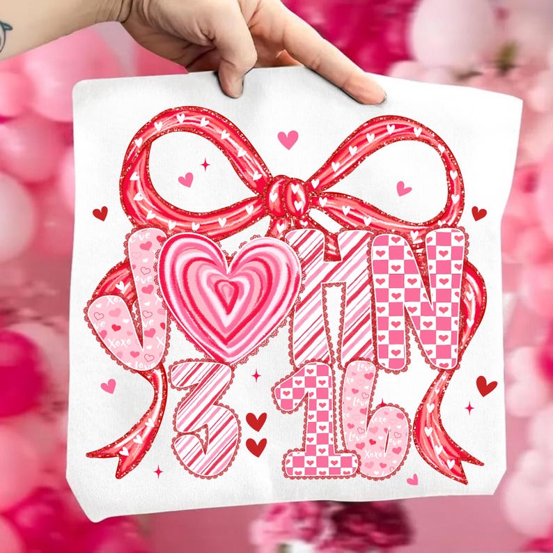 May include: A white tote bag featuring a large red bow with a heart-shaped design. The bag has the words "JOHN 3:16" in pink and red, with heart and star accents. The design is perfect for Valentine's Day.