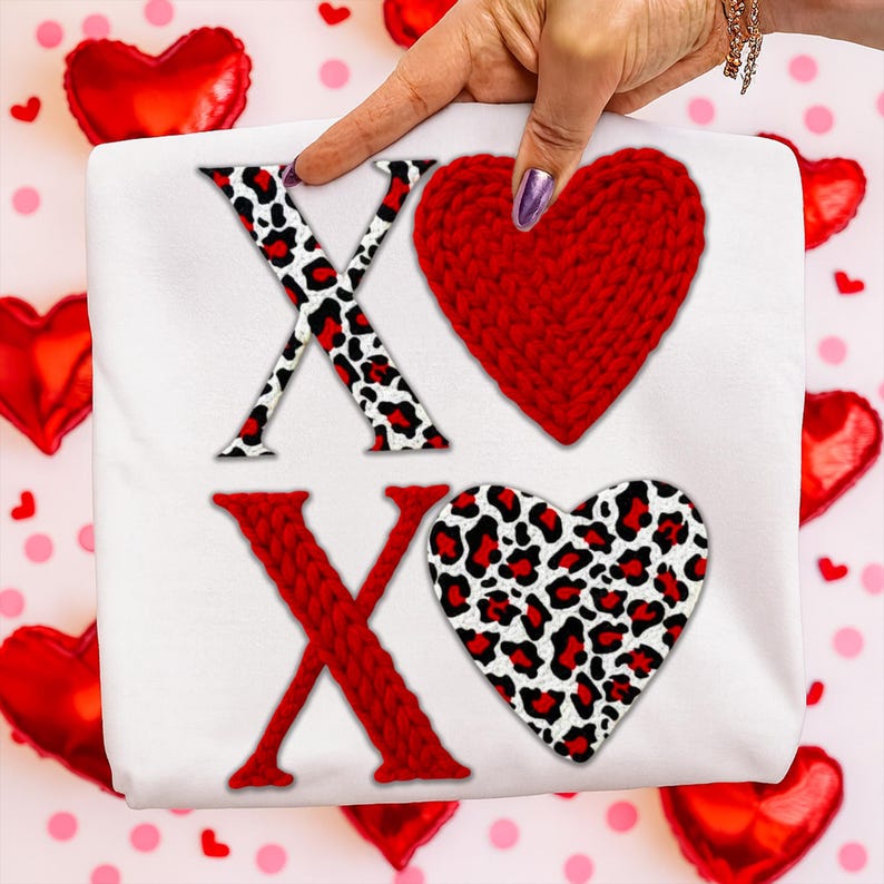Może przedstawiać: Biała tkanina z literami "XO". Litera "X" jest czerwona ze wzorem w panterkę, a "O" to czerwone dziergane serce. Drugie "X" jest czerwone, a drugie "O" to serce w panterkę. Czerwone balony w kształcie serca w tle.