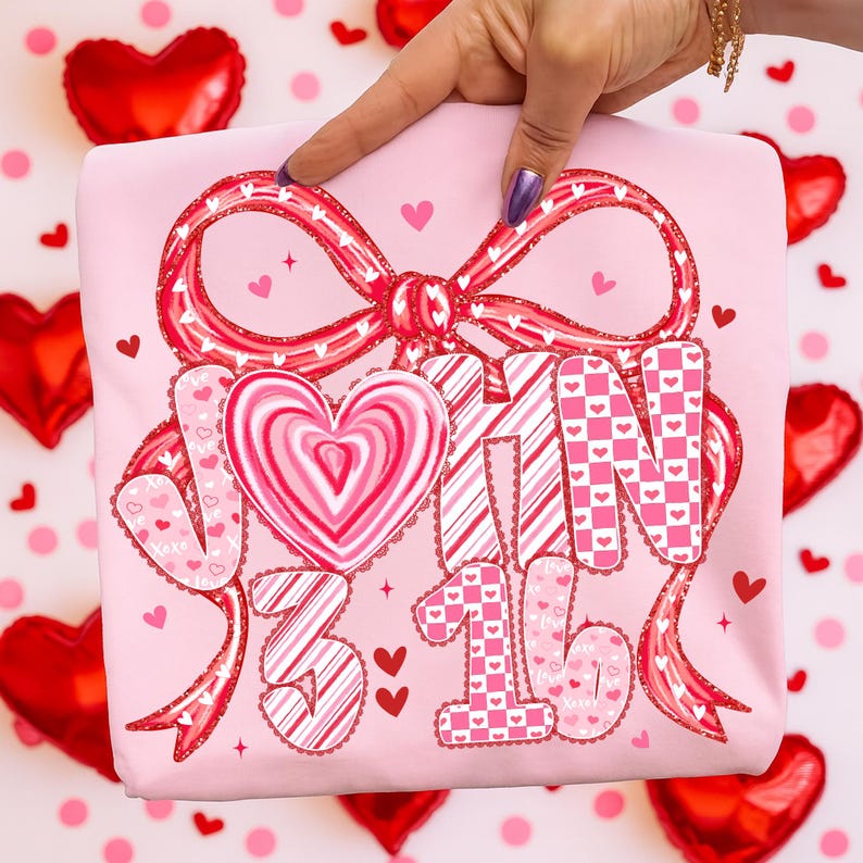 May include: A light pink t-shirt with a large red bow and the words "JOIN 3 16" in a decorative font. The letters and numbers are decorated with hearts and stripes. Small red hearts are scattered around the design.