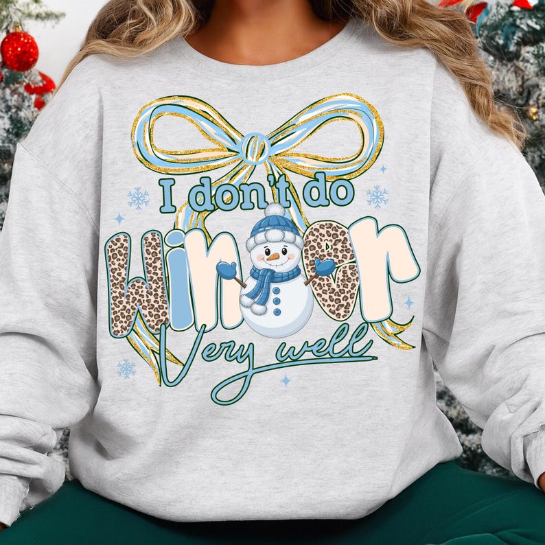 May include: A light gray sweatshirt with a winter-themed graphic. The design features a snowman wearing a blue hat and scarf, with the text "I don't do winter very well." The word "winter" has a leopard print pattern.