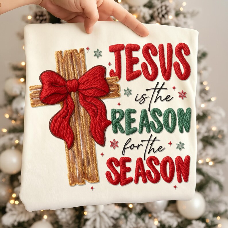 May include: Cream-colored sweatshirt with embroidered text and design. Features a wooden cross with a red bow, and the words "JESUS is the REASON for the SEASON" in red and green. Snowflake accents complete the festive design.