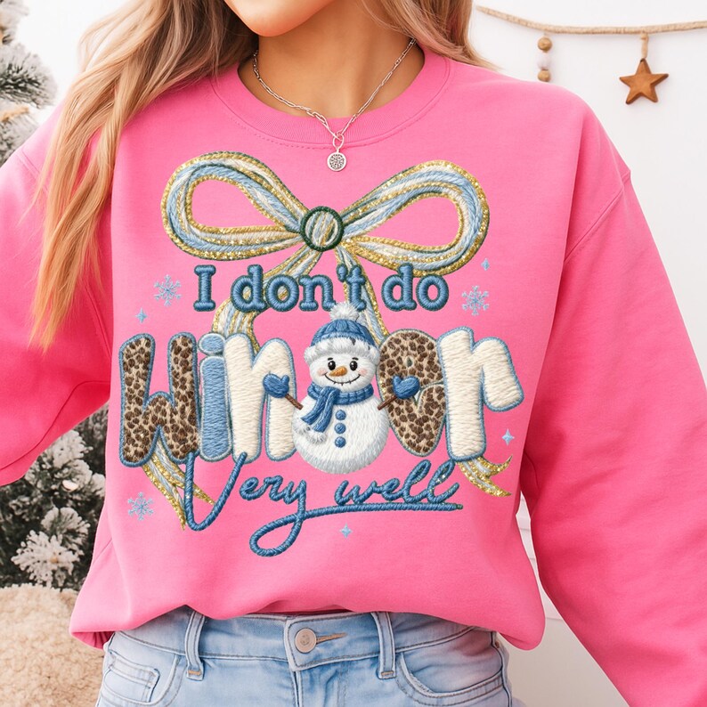 May include: A bright pink sweatshirt with the embroidered phrase "I don't do winter very well." The design includes a blue and gold bow, snowflakes, and a snowman wearing a hat and scarf. The sweatshirt has long sleeves.
