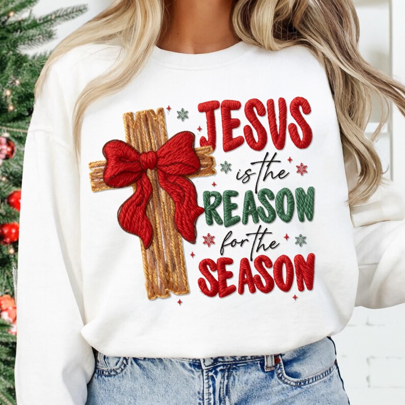 May include: White sweatshirt featuring a wooden cross with a red bow and the text "JESUS is the REASON for the SEASON" in red and green. The design includes snowflake accents, perfect for the Christmas holiday.