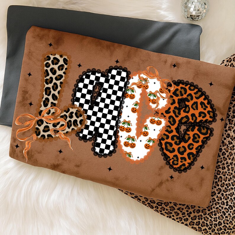 May include: Brown decorative pillow with the word "LOVE" in a mix of patterns. The "L" is leopard print, the "O" is a black and white checkerboard, the "V" is decorated with pumpkins, and the "E" is leopard print.