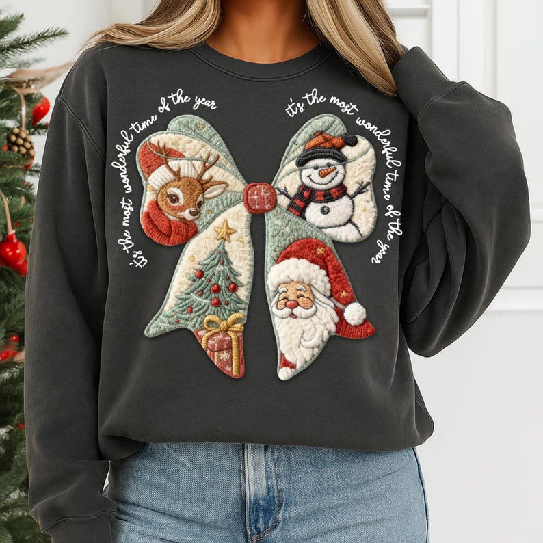 May include: Dark gray sweatshirt featuring a festive bow design with a reindeer, snowman, Christmas tree, and Santa Claus. The text "It's the most wonderful time of the year" is written around the bow. A cozy holiday-themed top.