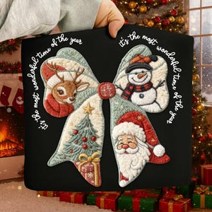 May include: Black Christmas-themed pillow featuring a bow design with a reindeer, snowman, Christmas tree, and Santa Claus. The text "It's the most wonderful time of the year" is written around the bow in white script.