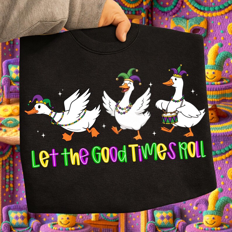 May include: Black sweatshirt featuring three white cartoon geese in Mardi Gras attire. Each goose wears a jester hat and beaded necklace. The text "Let the Good Times Roll" is printed in colorful letters across the bottom.