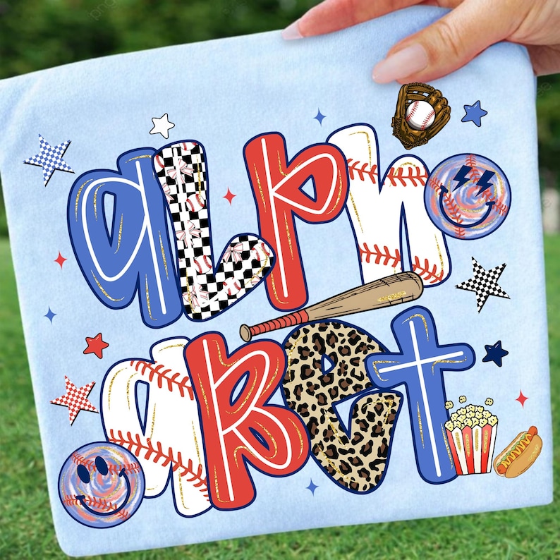 Op de afbeelding: Lichtblauw T-shirt met de woorden "ALMOST BASEBALL" in rood, wit, blauw en luipaardprint. Honkbalthema-afbeeldingen zijn onder meer een knuppel, bal, handschoen, sterren en een smiley.