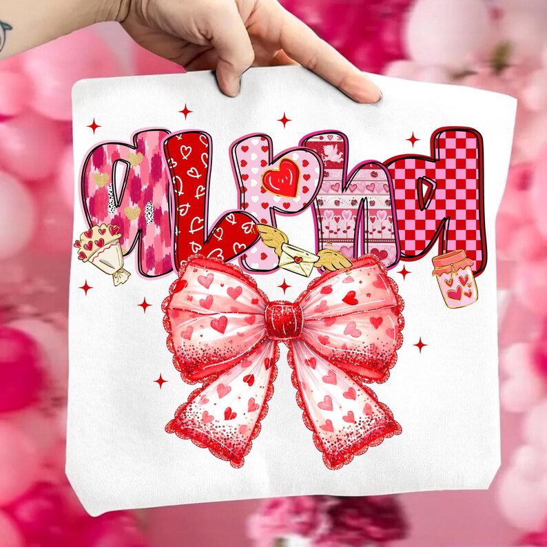 May include: White tote bag with the word "ALL YOU NEED" in pink and red letters. The letters have heart and floral patterns. A large red bow with heart details is at the bottom. Valentine's Day themed.