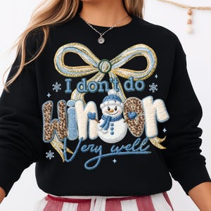 May include: Black sweatshirt with the text "I don't do winter very well." The design includes a snowman, a bow, and snowflakes. The word "winter" has a leopard print pattern.