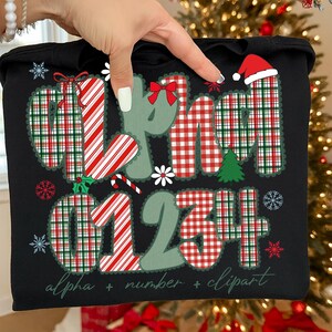 May include: Black tote bag with a Christmas-themed design. The design includes the words "alpha," "number," and "clipart," along with the numbers "01234." The letters and numbers are decorated with red and green plaid patterns, candy cane stripes, and snowflakes.