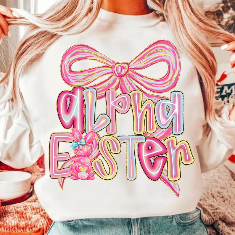 May include: White sweatshirt with a large pink bow and the words "Alpha Easter" in a colorful, outlined font. A pink bunny with a blue bow is also featured in the design. The design has a pastel color scheme.
