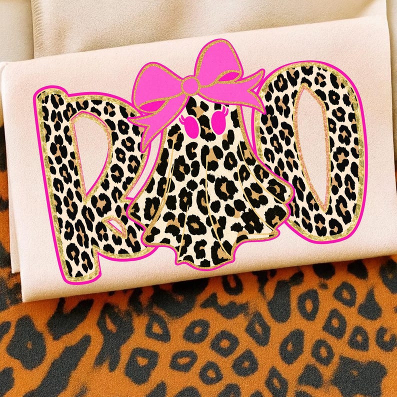 May include: A light pink fabric with a leopard print design that spells out the word "RAD". The letter outlines are gold with a leopard print pattern. A pink bow and a ghost with pink eyes are in the center.