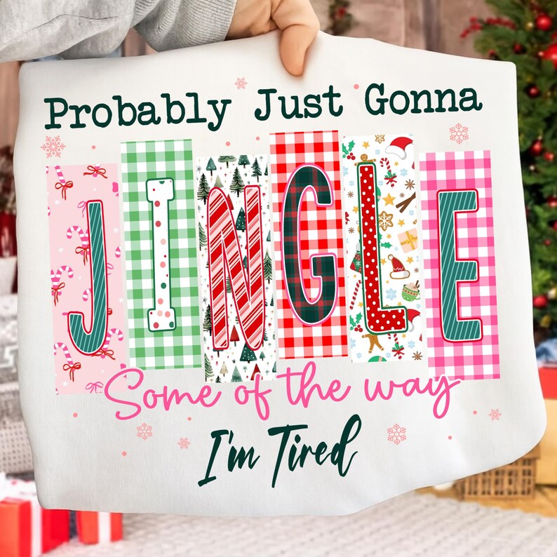 May include: White sweatshirt with the text "Probably Just Gonna Jingle Some of the way I'm Tired". The word "JINGLE" is in colorful block letters with Christmas-themed patterns, including candy canes, trees, and plaid.