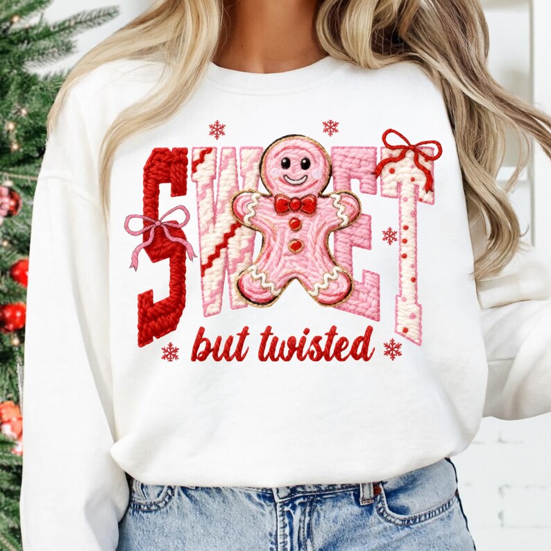 May include: White sweatshirt with the words "SWEET" and "but twisted" in red and pink embroidery. A pink gingerbread man with a red bow tie is in the center. Red bows and snowflakes are also embroidered on the sweatshirt.