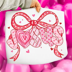 May include: A white sheet with the word "JESUS" in pink, heart-themed lettering, and a red bow. The letters are decorated with hearts and patterns. Small hearts and stars are scattered around the design, perfect for Valentine's Day.