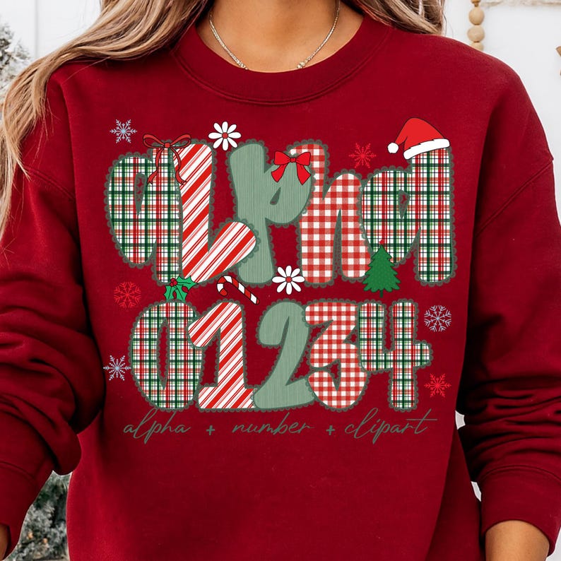 May include: A red sweatshirt with a festive design. The design includes the word "alpha" and numbers 0, 1, 2, 3, and 4, along with snowflakes, a Christmas tree, and a Santa hat. The text "alpha + number + clipart" is also included.