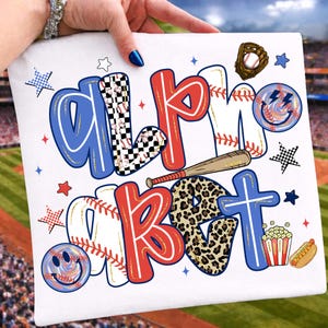 Op de afbeelding: Wit T-shirt met het woord "ALPHABET" in een honkbalthema. De letters zijn versierd met honkballen, luipaardprint en dambordpatronen. Een honkbalknuppel, handschoen en voedseliconen maken het ontwerp compleet.