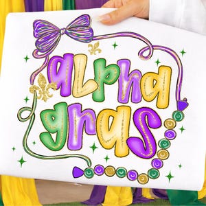 May include: White square with the words "Alpha Gras" in green, purple, and gold lettering. The design includes a purple bow, fleur-de-lis, and a string of beads in Mardi Gras colors. Green and gold glitter accents the design.