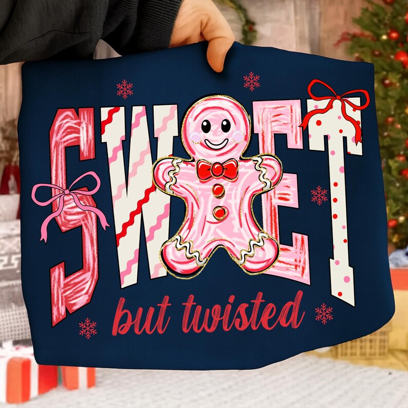 May include: Navy blue cushion featuring the words "SWEET" and "but twisted" in red and pink. A pink gingerbread man with a red bow tie is in the center. Pink bows and snowflakes decorate the design.