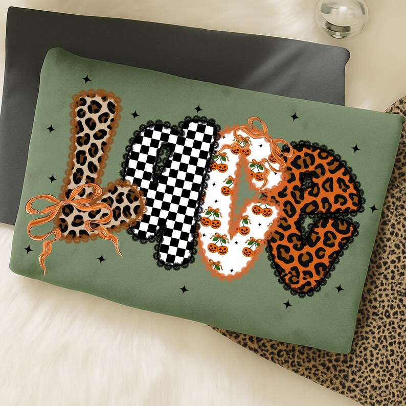 May include: Green decorative pillow with the word "LOVE" in a mix of patterns. The "L" is leopard print, the "O" is a black and white checkerboard, the "V" is decorated with pumpkins, and the "E" is leopard print. The pillow has a black lace trim.