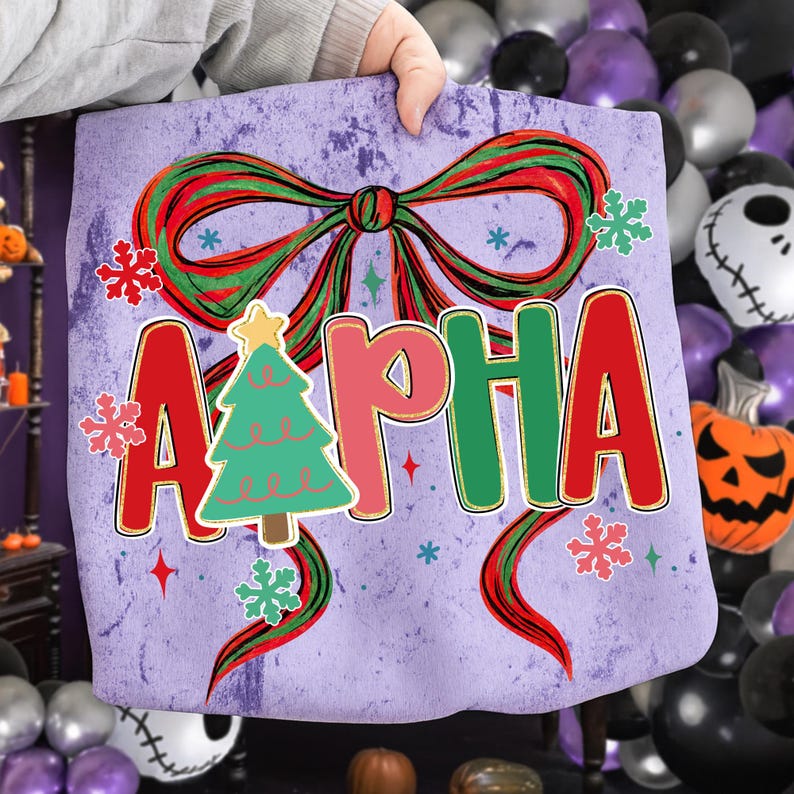 May include: A purple tote bag featuring a large red and green bow, snowflakes, and the word "ALPHA" in red, pink, and green letters. A green Christmas tree with a yellow star is in the center. The bag is held by a person.