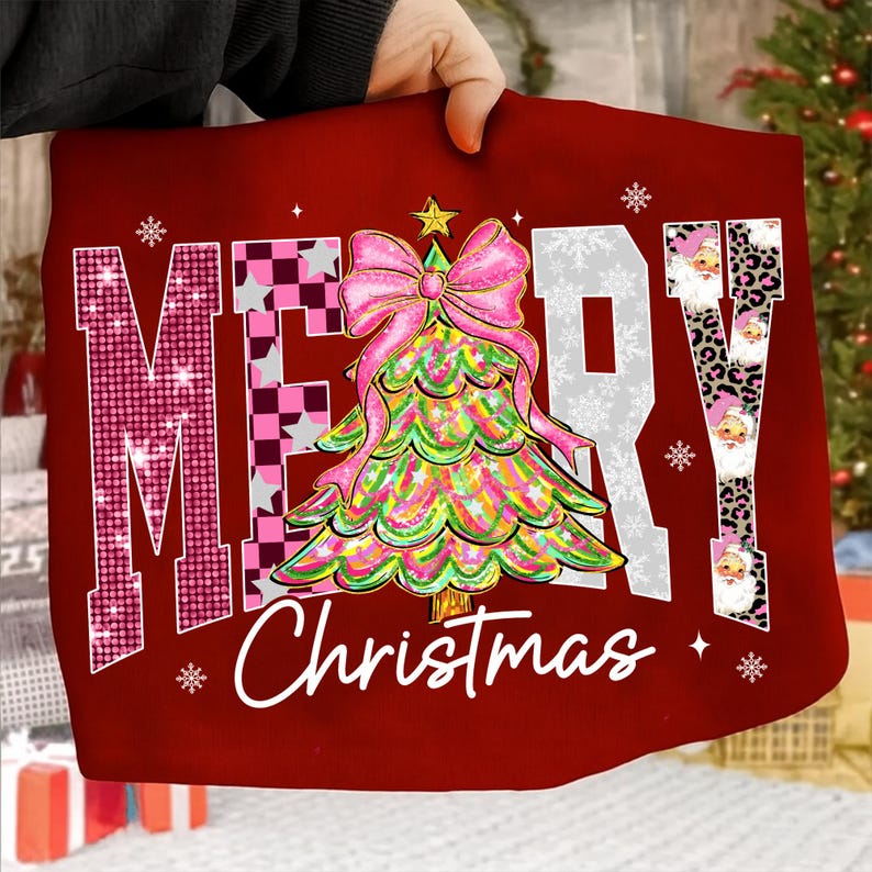May include: A red Christmas-themed pillow with the words "MERRY Christmas" in a festive design. The "M" is pink with sequins, the "E" has a pink and black checkered pattern, and the "R" is white with snowflakes. A colorful Christmas tree with a pink bow is in the center.