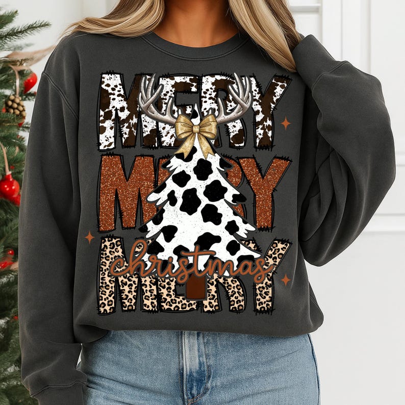 May include: Dark gray sweatshirt with a festive Christmas design. The design features the words "MERRY CHRISTMAS" in a mix of cow print, leopard print, and brown textures. A cow-print Christmas tree is in the center, topped with antlers and a gold bow.