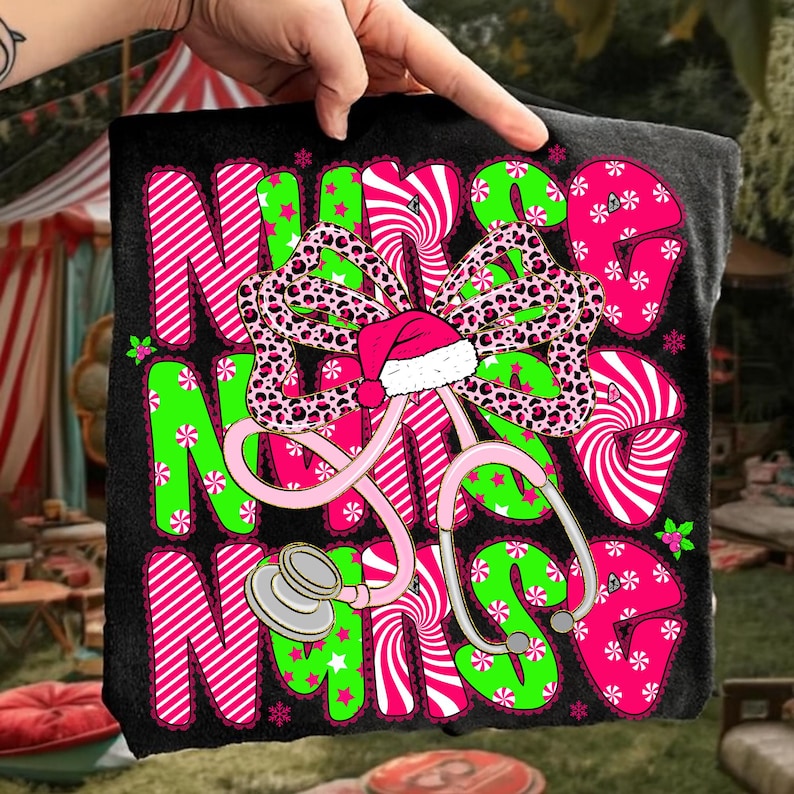 May include: Black t-shirt with the word "NURSE" in pink and green, decorated with a bow, Santa hat, and stethoscope. The bow has a leopard print design. The letters are decorated with stripes, stars, and snowflakes.