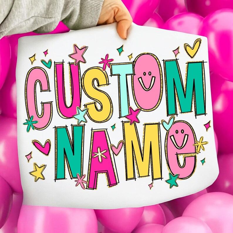 May include: A white sign with the words "CUSTOM NAME" in colorful, playful lettering. The letters are outlined in gold glitter and decorated with stars, hearts, and smiley faces. The background is a cluster of pink balloons.