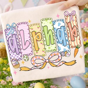 May include: A cream-colored Easter-themed design featuring the word "Alpha" in colorful, decorative letters. Each letter is on a vertical banner with pastel colors, bows, and Easter egg details. A large bow and carrot are also included in the design.
